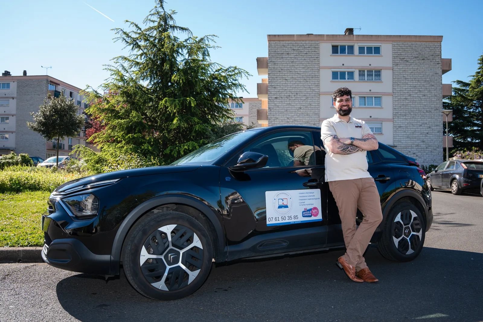 Pierrick Le Penru, informaticien à domicile, devant sa voiture aux couleurs d'Aide Numérique 37 dans un quartier résidentiel